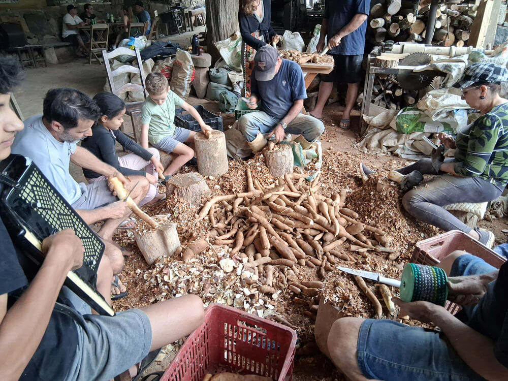 Roda de pessoas descascando mandioca
